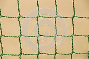 Detail of crossed green soccer nets, soccer football in goal net with natural grass on football playground in the background