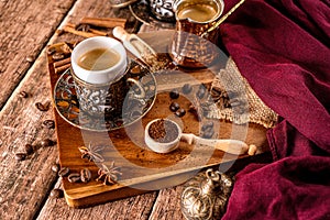 Detail of a cup of coffee and coffee beans on wood background