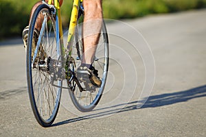 Detail of cyclist man feet riding bike on road.