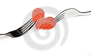 Detail of decorative red heart near forks on white background, valentine day dinner on white background