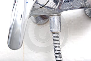 Detail of dirty calcified shower mixer tap and shower hose, faucet with limescale or lime scale on it, close up