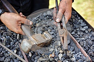 Detail of dirty hands holding hammer and pliers