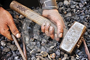 Detail of dirty hands holding hammer and rod