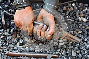 Detail of dirty hands holding pliers