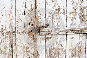 Detail of doorlock in wooden plank wall with peeling white color