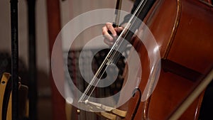 detail of the double bass and the hands of a musician playing on the strings