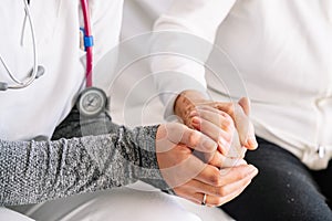 Detail of an elderly woman's hands being caressed by the hands of a young nurse