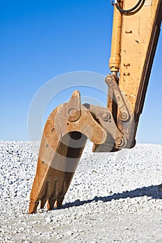 Detail of excavator`s bucket at a gravel seaside