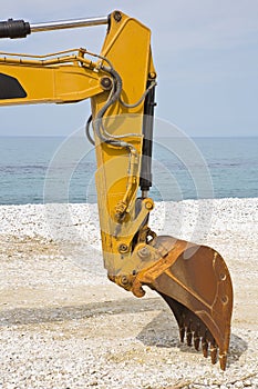 Detail of excavator`s bucket at a gravel seaside