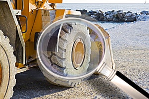 Detail of the excavator`s wheel at the seaside - Concept image seen through a magnifying glass