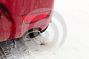 Detail on exhaust pipe of a red car parked on snow