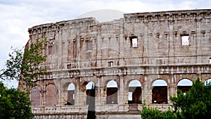 Detail of the facade with arches of the Colosseum Amphitheatrum Flavium with trees in front