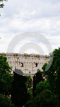 Detail of the facade with arches of the Colosseum Amphitheatrum Flavium with trees in front photo