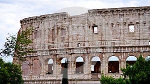 Detail of the facade with arches of the Colosseum Amphitheatrum Flavium with trees in front photo