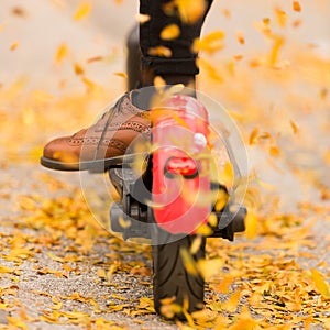 Detail of fashinable hipster girl riding electric scooter in park at fall photo