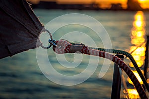 Detail of fastening the sail on a yacht in the rays of the sunset. Shooting on board a yacht on the river