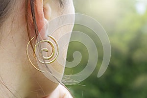 Detail of female ear wearing metal decorative shape earring