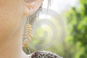 Detail of female ear wearing metal decorative shape earring