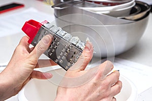 Detail of female hands grate cheese. Women prepare cheese in the kitchen for pizza or pie.Baking concept