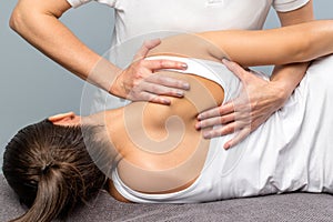 Detail of female therapist manipulating shoulder blade on patient.