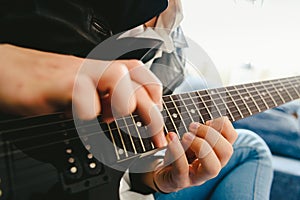 Detail of the fingers of a guitarist placed on the fret of the mast of the guitar playing a chord doing Tapping