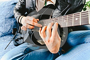 Detail of the fingers of a guitarist placed on the fret of the mast of the guitar playing a chord doing Tapping