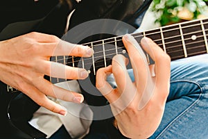 Detail of the fingers of a guitarist placed on the fret of the mast of the guitar playing a chord doing Tapping