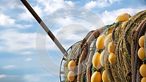 Detail of a fishing net collected in the back of a fishing boat with a blue sky in the background