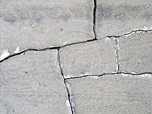 Detail of fractured concrete sidewalk floor, gray grunge cement surface with large cracks