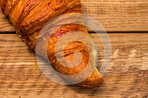 Detail of fresh croissant on wooden table. Food and breakfast concept. Top view and copy space