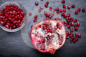 Detail of the fresh pomegranate seeds and juicy pomegranate fruit on the dark slate background