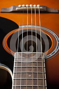 Detail of the fretboard and body of an acoustic guitar, shallow depth of field