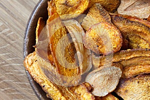 Detail of fried carrot and parsnip chips in rustic wood bowl.