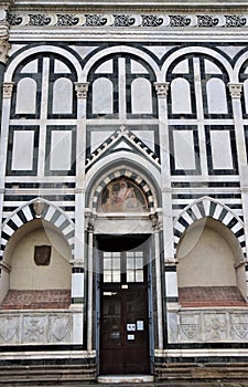 Detail of the front wall of Santa Maria novella with a wooden door and two niches in the side wall in Florence.