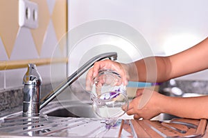 Detail of a girl`s hands placing a freshly scrubbed glass to dry. Helping with housework