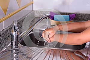 Detail of a girl`s hands. Rinsing her hands in the kitchen sink. Washing her hands. Concept of cleaning