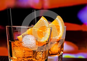 Detail of glasses of spritz aperitif aperol cocktail with orange slices and ice cubes on bar table, vintage atmosphere background