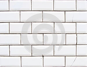 Detail of a glossy white beveled tile wall with damage