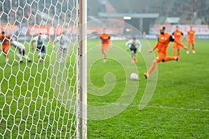 Detail of goal's post with net and football player during penalty kick