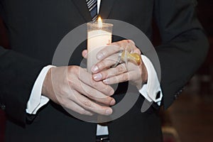 Detail of the godfather,s hands holding a candle and pacier