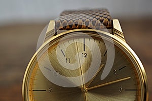 Detail of a golden watch with indented gold-plated crown as a symbol of time or exactness