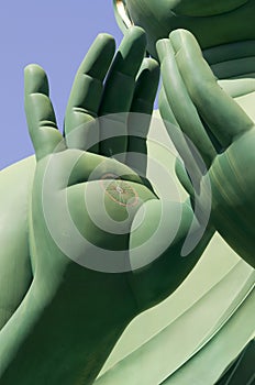 Detail of green hands of buddha with dharma wheel