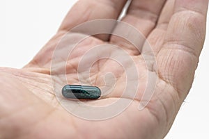 Detail of a green pill in the palm of the hand