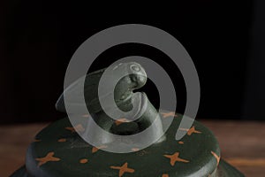Detail of green traditional chinese Yixin clay teapot with cicada on the cover. On the wooden table and black backround