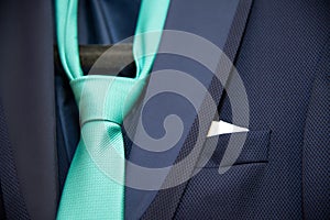 Detail of a groom`s dark blue costume and a green tie