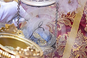 Detail of the hand of an altar boy or acolyte in a Holy Week procession filling one of the censers with incense