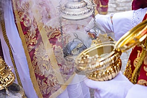 Detail of the hand of an altar boy or acolyte in a Holy Week procession filling one of the censers with incense