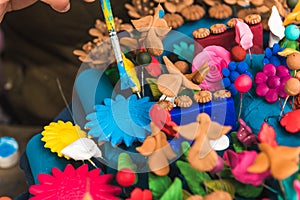 Detail of the hand of an artisan painting a tree of life made of clay in different colors with a brush