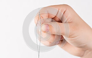 Detail of hand holding needle with thread on white background