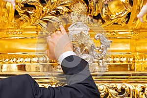 Detail of the Hand of the main brother Hermano mayor of a holy week procession that is hitting the  knocker llamador to give photo